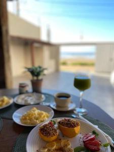 Una mesa con platos de comida y una copa de vino. en Casa Pé Na Areia - Praia Grande ES, en Fundão