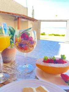 una mesa con dos copas de vino y un bol de fruta en Casa Pé Na Areia - Praia Grande ES, en Fundão