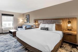a hotel room with a large bed and a couch at Best Western Plus Bourbonnais Hotel & Suites in Bourbonnais