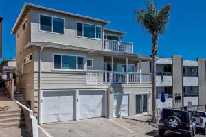 a house with white garage doors and a palm tree at Monterey B in San Clemente