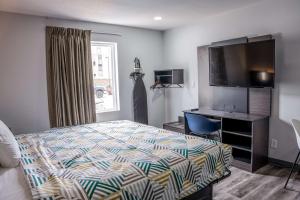 a bedroom with a bed and a desk and a television at Studio 6 Claremore OK in Claremore