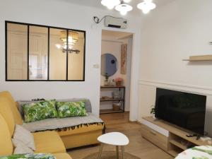 a living room with a yellow couch and a flat screen tv at Patxikuenea in Zarautz