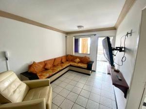 a living room with a couch and a television at Apartamento Castelhanos ES in Anchieta