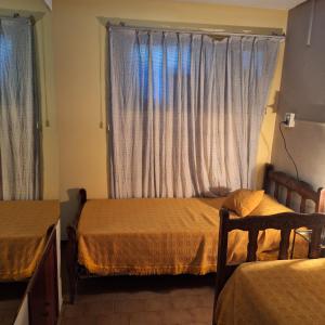 a bedroom with two beds and a window with curtains at AMPLIO DEPARTAMENTO temporario in La Plata