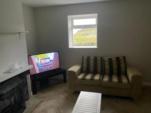 a living room with a couch and a television at Sea View Cottage in Clonmany