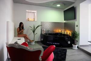 a woman sitting in a living room with a fireplace at La Suite di FiloGà in Vieste