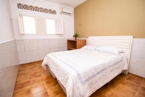 a bedroom with a white bed and two windows at Quarto amplo ao lado do mar in João Pessoa