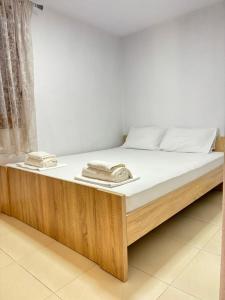 a bed with a wooden frame and white sheets at Garden Haven 100m from the Sea in Siviri