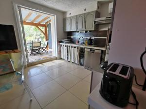 una cucina con porta aperta su un patio di Bas de villa avec jardin, piscine et jacuzzi a La Seyne-sur-Mer