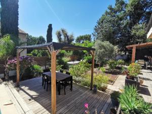 una terrazza in legno con tavolo e ombrellone di Bas de villa avec jardin, piscine et jacuzzi a La Seyne-sur-Mer