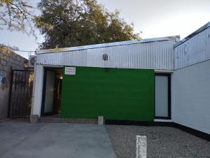 a green garage door on a white building at Takú Huasi in La Rioja +4 photos