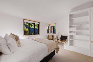 une chambre blanche avec un grand lit et une chaise dans l'établissement Fabulous Home with Great Views, à Queenstown