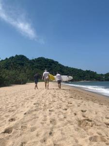trois personnes marchant sur la plage avec leurs planches de surf dans l'établissement Villa Cocos #4, à San Francisco