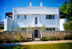 a white house with a stone fence at Cottesloe Bel-Air Apartment in Perth