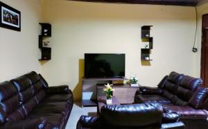 a living room with leather couches and a flat screen tv at Departamentos las Palmeras in Tarapoto
