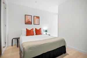 a bedroom with a bed with two orange pillows at Modern, Luxury Retreat with Gym and Pool in Melbourne +11 photos