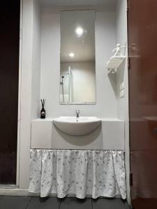 Un baño blanco con lavabo y espejo. en Mokkwa Mansion, Hat yai, en Hat Yai 6 fotos más