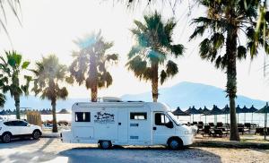 a white truck parked in a parking lot with palm trees at Camper Van For Rent in Tirana