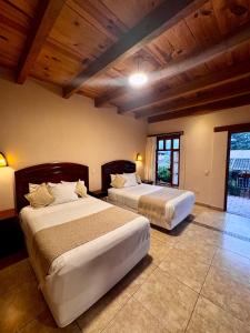 two beds in a bedroom with wooden ceilings at Parador Margarita in San Crist&oacute;bal de Las Casas