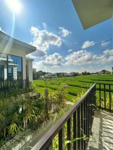 a house with a balcony with a view of a green field at EL Suites Berawa - Canggu in Canggu