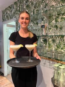 a woman holding a tray with two martini glasses at Kellys Beach Resort in Bargara +50 photos