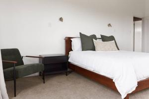 a bedroom with a bed and a chair at Pohutukawa Point Estate Homestead in Karaka +19 photos