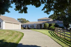 a house with a fence and a driveway at Pohutukawa Point Estate Homestead in Karaka