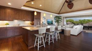 an open kitchen and living room with a bar with stools at HAWAIIAN BLISS Relax and Reconnect in KaMilo 4BR Home With Views in Waikoloa
