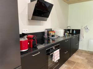 una cucina con ripiani neri e un elettrodomestico rosso di Échappez-vous à la campagne sarthoise: charme, nature, proximité 24H du Mans & zoo! - FR-1-410-448 a Mayet