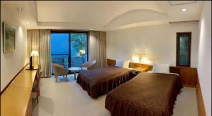 una camera d'albergo con due letti e un balcone di 箱根七福荘 a Onsensō