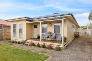 a small yellow house with two chairs on a deck at Cooinda at The Cape in Cape Woolamai