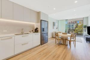 a kitchen with white cabinets and a table and a dining room at Miles at Kirra Point 303 in Gold Coast
