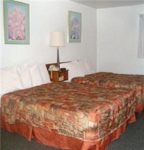 a hotel room with two beds and a lamp at Western Motel Ranchester in Ranchester