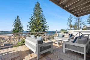 a patio with chairs and a tree on a balcony at Kaya in Collaroy