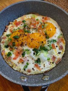 a breakfast pizza with eggs and vegetables on a pan at OCEAN LODGE in Pantai Cenang