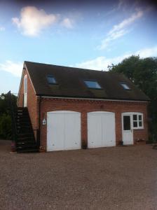 a brick building with two garage doors and a staircase at Stone Hill Farm B&B in Shrawley