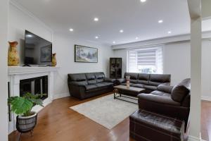 Una sala de estar con muebles de cuero y chimenea. en Beautiful House In Scarborough, en Toronto