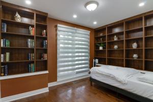 1 dormitorio con estanterías de libros, 1 cama y ventana en Beautiful House In Scarborough, en Toronto