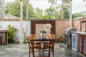 a patio with a table and chairs and a grill at Tropik Resort Lombok in Selong Belanak