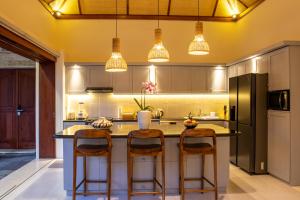 a kitchen with a large island with bar stools at Tropik Resort Lombok in Selong Belanak