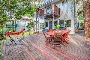 a wooden deck with a table and chairs at Paperbarks by the beach in Hawks Nest