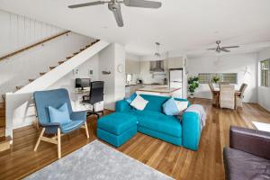 a living room with a blue couch and chairs at Paperbarks by the beach in Hawks Nest
