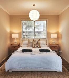 une chambre avec un grand lit blanc avec deux lampes dans l'établissement Banksia Retreat, A couple's sanctuary on Aldinga Beach, à Aldinga Beach