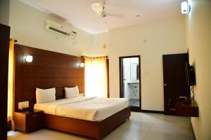 een slaapkamer met een groot bed en een televisie bij Nijaguna Resorts in Chāmrājnagar +33 foto's