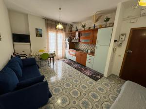 a living room with a blue couch and a kitchen at Appartamento Primavera in Scalea