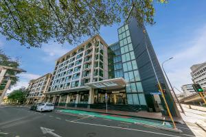 a tall building on a city street with a white car at Fabulous Corner Apartment w/ Dazzling Harbour View in Auckland