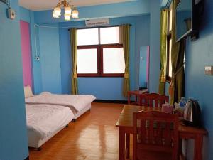 a room with two beds and a table and a window at Royal Land Mae Klong Hotel in Samut Songkhram