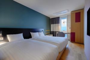 a bedroom with a large white bed and a window at SONO MOON Haeundae in Busan