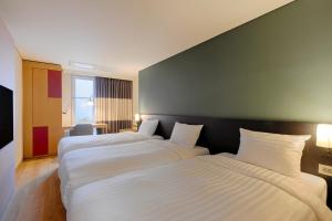 two beds in a hotel room with white sheets at SONO MOON Haeundae in Busan