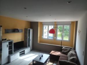 a living room with a couch and a red lamp at Appartement Volmunster in Volmunster